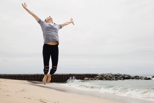 Exuberant Woman Jumping For Joy On Beach