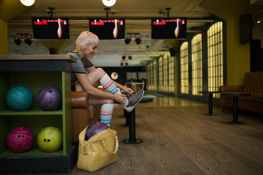 Young woman putting on bowling shoes bowling alley