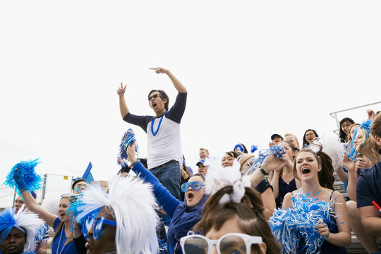 Enthusiastic man in blue standing cheering in bleachers