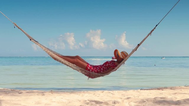 Girl relaxing in a hammock on tropical island beach. Summer vacation in Punta Cana, Dominican Republic