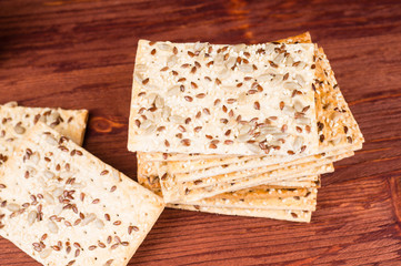 Stack of crispy wheat cakes with sesame seeds, flax and sunflower on a red wooden background. Top view.  vegetarian food, eco food concepts