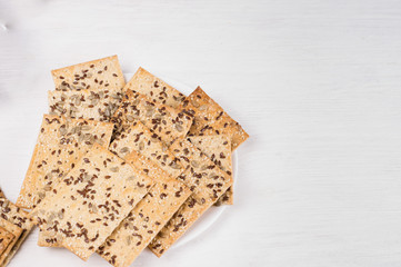 crispy wheat cakes with sesame, flax and sunflower seeds on plate on white wooden background. vegetarian food, eco food concepts