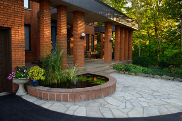 Front entrance with pond and stone veranda on red brick house with pillars