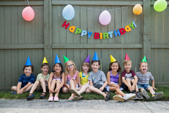 Portrait smiling kids a row backyard birthday party