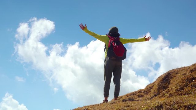 Rear view of female hiker enjoying fresh air while screaming on the top of mountain. Shot in 4k resolution