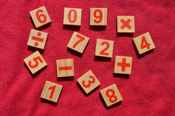 Fototapeta na wymiar Wooden numbers and mathematical symbols placed on a pink background Use in learning.
