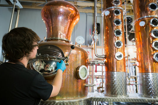 Worker checking copper distillery vats