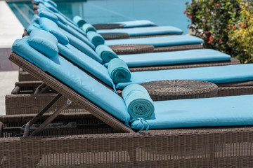 Closeup of towels on lounge chairs near a luxury swimming pool at a tropical resort spa in island...