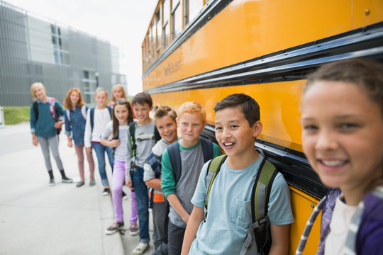 Portrait Smiling School Kids Leaning On School Bus