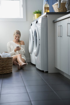 Woman Texting With Cell Phone Laundry Room Floor