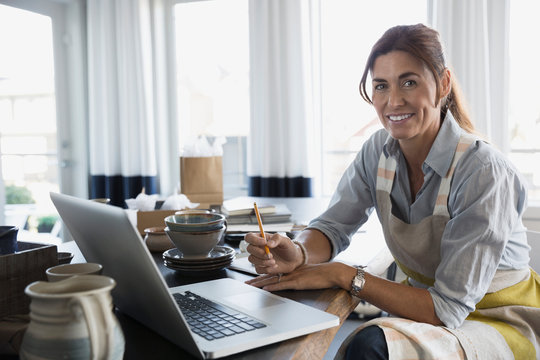 Portrait smiling woman with pottery at laptop