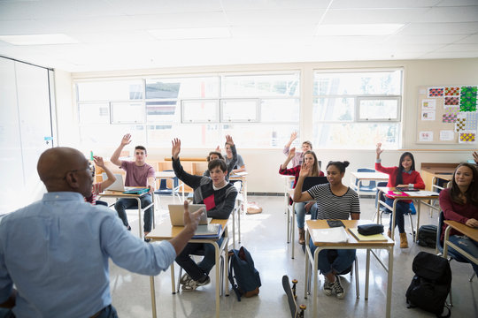 High school teacher calling students with hand raised