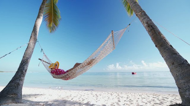 Girl relaxing in a hammock on tropical island beach. Summer vacation in Punta Cana, Dominican Republic