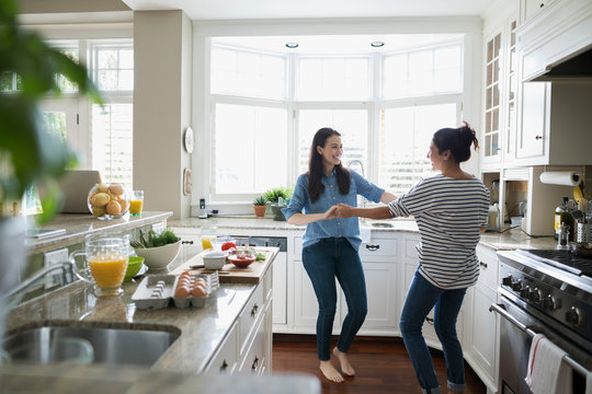 Mother and daughter dancing in kitchen