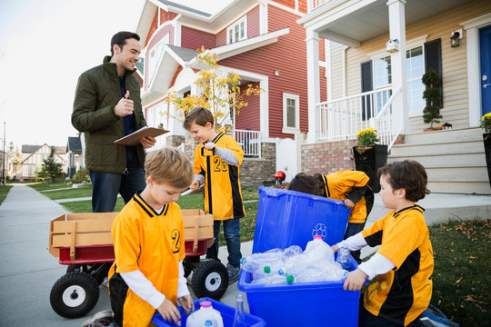 Coach and boys sports team gathering recycling neighborhood
