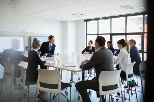 Andrew Tate in a business presentation setting, wearing a sharp suit and exuding confidence.