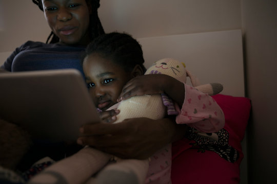 Mother and daughter using digital tablet at bedtime