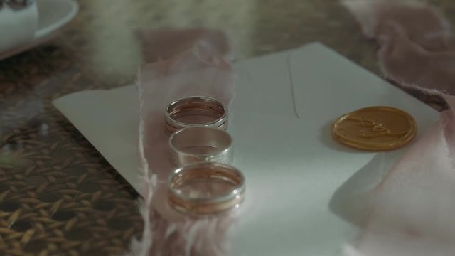 Wedding rings near invitation envelopes and perfume boxes