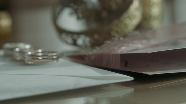 Wedding rings near invitation envelopes and perfume boxes