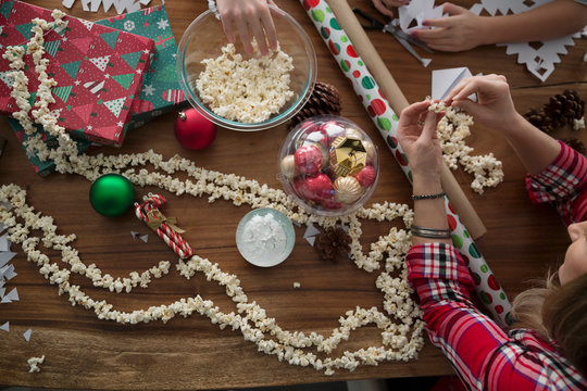 Mother and children stringing Christmas popcorn decoration