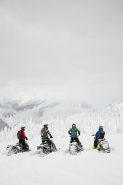 Men sitting on snowmobiles in remote snowy field
