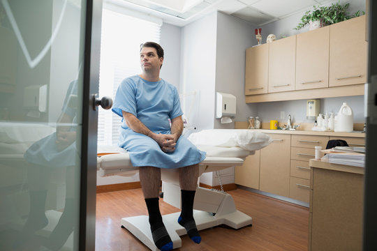 Patient in hospital gown waiting in examination room