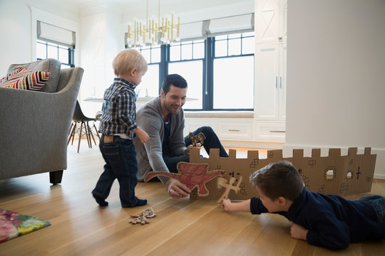 Father and sons playing with cardboard fort