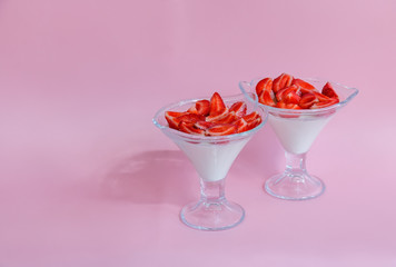 Homemade  italian dessert panna cotta with fresh strawberry in glass bowls on pink background. Selective focus.