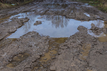 The bad ground or soil rural or suburb road or way with puddles, pools, mud and slush