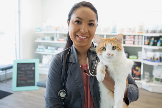 Portrait Smiling Veterinarian Holding Cat In Clinic