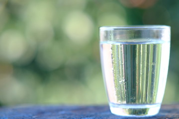 glass of water on green background of grass
