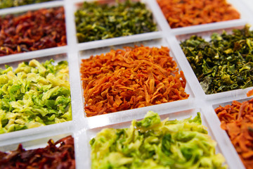 Sublimated thinly sliced vegetables. Dried carrots in the center of the frame. In neighboring cells, dried cabbage and beets are sprinkled.