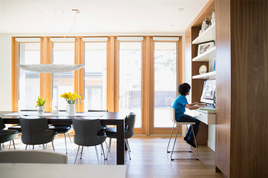 Boy using computer at desk in dining room