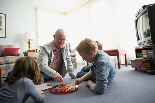 Grandfather and grandchildren playing Chinese checkers
