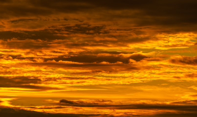 Naklejka na ściany i meble Beautiful sunset sky. Golden sunset sky with beautiful pattern of clouds. Orange, yellow, and dark clouds in the evening. Freedom and calm background. Beauty in nature. Powerful and spiritual scene.