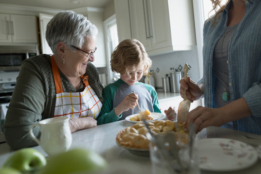Multi-generation family eating homemade pie in kitchen