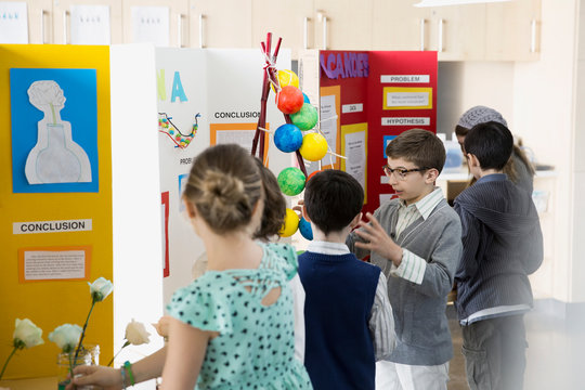School boy explaining science fair project to classmates