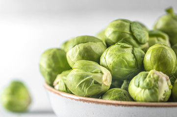 Organic raw and fresh brussel sprouts on a plate on light background