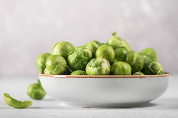 Organic raw and fresh brussel sprouts on a plate on light background