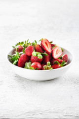 Heap of fresh strawberries in ceramic bowl on white background