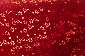 Obraz na płótnie Canvas Blurred holiday red background with star-shaped highlights.