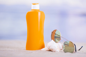 Orange plastic bottle with sunglasses and seashell