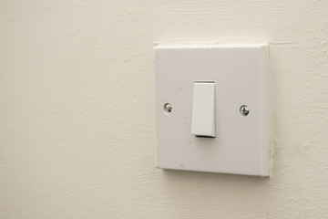 A simple white electrical light switch on a white wall. Industrial, residential or DIY construction...