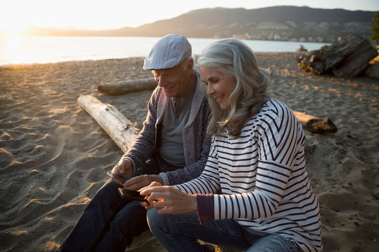 Senior couple texting the cell phones on sunset beach