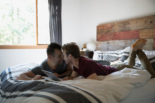Affectionate homosexual couple with digital tablet on bed