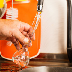 A man pours tap water into a glass flask.
