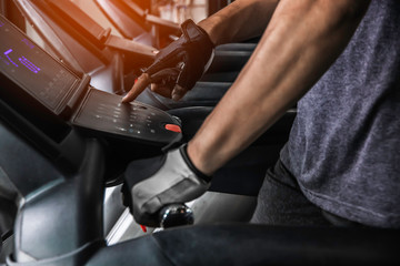 Close up hand turn on treadmill, finger pressing on button of running machine in gym