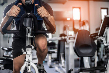 Fitness man doing exercise bike for cardio workout at gym.