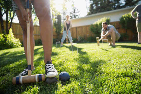 Friends playing croquet in sunny backyard