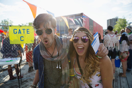 Portrait enthusiastic young couple with summer music festival tickets outside gate